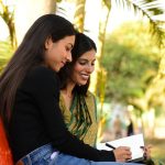 smiling friends writing in park with palm trees
