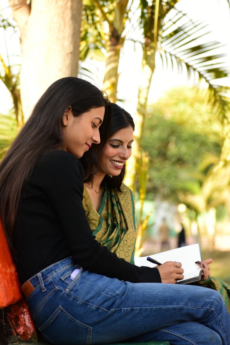 smiling friends writing in park with palm trees